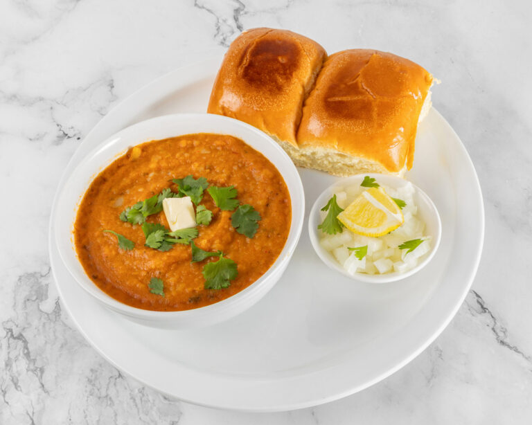 Mumbai style pav bhaji served with buttered pav buns, chopped onions and lemon